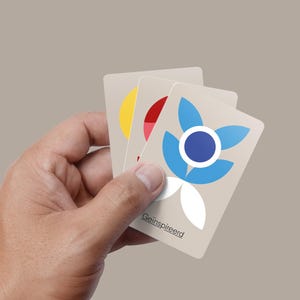Può includere: Tre carte con un designo floreale stilizzato. Il fiore ha petali blu e un cerchio blu al centro. Le carte sono bianche con il testo "Geïnspireerd" in basso.