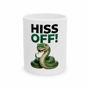Peut inclure: Un mug en céramique blanc orné d'un dessin de serpent vert enroulé avec une langue rouge. Au-dessus du serpent, le texte HISS OFF! est imprimé en lettres capitales noires et vertes. Le motif est centré sur le devant du mug cylindrique.
