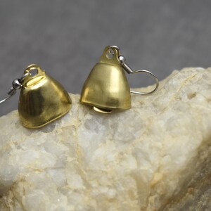 May include: A pair of gold-toned metal bell-shaped earrings featuring a smooth, polished finish. Each earring is attached to a silver-toned metal hook wire, designed for pierced ears, showcasing a simple, functional, and classic bell silhouette.