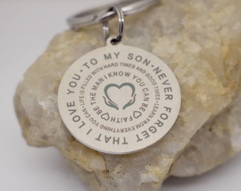 May include: A circular silver-toned metal keychain engraved with the text: TO MY SON NEVER FORGET THAT I LOVE YOU LIFE IS FILLED WITH HARD TIMES AND GOOD TIMES LEARN FROM EVERYTHING YOU CAN BE THE MAN I KNOW YOU CAN BE FAITH.