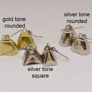 May include: Three pairs of bell-shaped earrings with fishhook wires. One pair is gold tone rounded, one is silver tone rounded, and one is silver tone square. Text labels read: gold tone rounded, silver tone rounded, and silver tone square.
