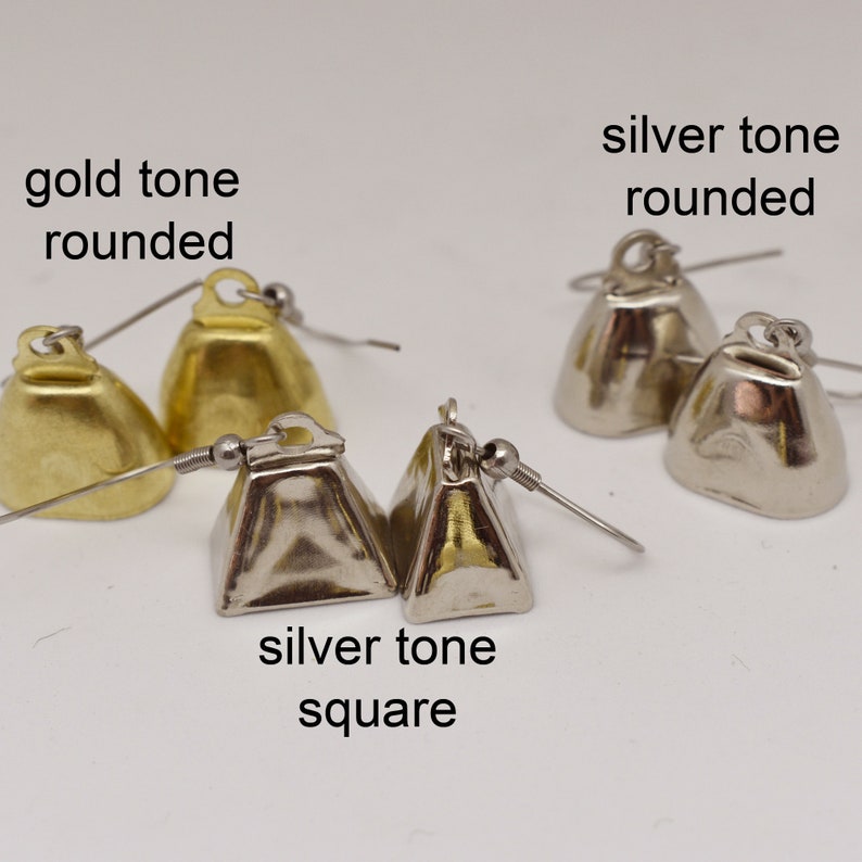 May include: Three pairs of bell-shaped earrings with fishhook wires. One pair is gold tone rounded, one is silver tone rounded, and one is silver tone square. Text labels read: gold tone rounded, silver tone rounded, and silver tone square.