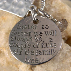 A 1 1/8 inch stainless steel disc with "Sister to Sister we will always be, a couple of nuts off the family tree", with a tree charm with "Sister" underneath the tree. A faceted clear glass bead for accent.