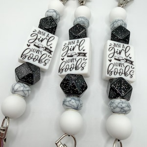 May include: Three beaded lanyards with silver-tone clasps. Each lanyard features white, black, and gray beads, including a rectangular charm that reads "Just a girl who loves books" in black script.