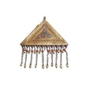 May include: A triangular pendant with intricate metalwork and dangling chains. The pendant features a gold-toned frame with detailed patterns, turquoise accents, and a central design. Small chains with beads and coral-colored accents hang from the bottom.