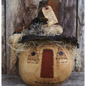 May include: A handmade primitive scarecrow with a burlap face, stitched features, and a straw hat with a crow perched on top. The scarecrow has a red fabric nose and a tag that says "Scarlett".