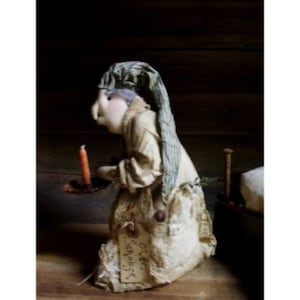 May include: A handmade rag doll wearing a blue and white striped nightgown and a green and white striped sleep cap. The doll is holding a candle and is standing next to a small wooden bed. The doll has a tag that says "Good Night!"