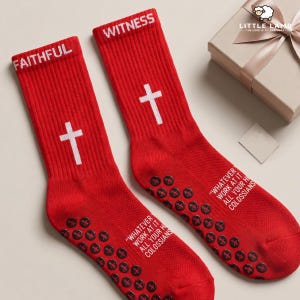 May include: Two red socks with white crosses and the words "FAITHFUL" and "WITNESS" at the top. The phrase "WHATEVER WORK AT IT ALL YOUR H COLOSSIANS" is printed on the sides. The socks have black grips on the soles.
