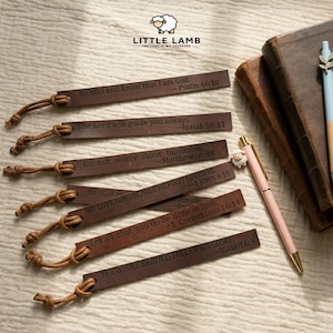 Könnte beinhalten: Eine Sammlung brauner Leder-Lesezeichen mit inspirierenden Zitaten und Bibelstellen. Jedes Lesezeichen hat eine geknotete Kordel und wird mit einem rosa Stift und einem blauen Stift präsentiert. Das Little Lamb-Logo ist sichtbar.