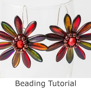 Puede incluir: Un par de pendientes de flores con cuentas de vidrio iridiscente rojo, naranja, amarillo, verde y morado. Los pendientes cuelgan de ganchos plateados.