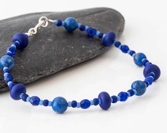 Könnte beinhalten: Ein blaues und silbernes Perlenarmband mit einem silbernen Verschluss. Das Armband besteht aus einer Mischung aus runden und facettierten Perlen in Blautönen.