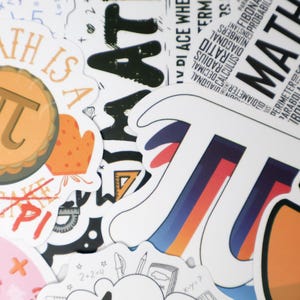 Può includere: Una collezione di adesivi colorati a tema matematico. Gli adesivi presentano il simbolo pi greco, le parole "MATH IS A PIECE OF CAKE" e termini matematici come "raggio" e "diagonale". Gli adesivi sono di varie forme e dimensioni.