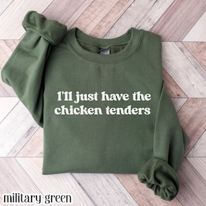 May include: Military green sweatshirt with the text "I'll just have the chicken tenders" in white. The sweatshirt has a crew neck and long sleeves.