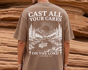 Camiseta cristiana de colores cómodos para hombre "Deposita todas tus preocupaciones, Señor" 1 Pedro 5:7. Camiseta con estampado de naturaleza, río, pesca y barco. Versículo bíblico religioso.