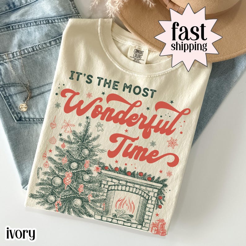 Ivory Christmas shirt with “It’s the Most Wonderful Time” text, featuring a decorated Christmas tree, fireplace, ornaments, and holiday accents in vintage-style artwork