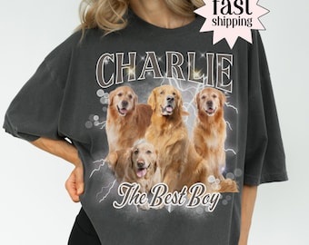 May include: Dark gray t-shirt featuring a graphic of four golden retrievers with the name "Charlie" above and "The Best Boy" below. The design includes lightning bolt accents. The shirt has a vintage, worn look.