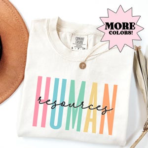 White Comfort Colors t-shirt featuring colorful “Human Resources” lettering, a fun and stylish HR professional shirt perfect for office wear, work events, and unisex soft cotton apparel