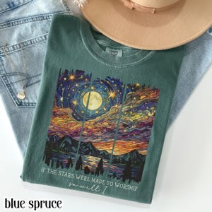 Blue spruce Comfort Colors t-shirt featuring a vibrant celestial night sky landscape with a full moon, stars, mountains, pine trees, and reflective water in a vertical panel design, with the printed text if the stars were made to worship so will I. Soft-washed cotton graphic tee