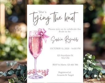 May include: A white card with a pink champagne glass and pink bow. The text on the card reads "She's Tying the Knot" and includes the bride-to-be's name, Sophia Reynolds, the date and time of the event, the location, RSVP information, and where the couple is registered.