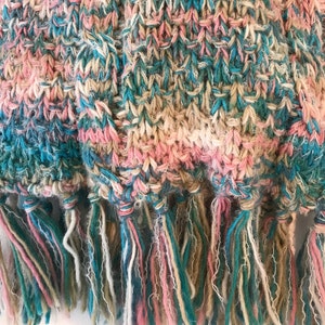 May include: A knitted scarf with a fringe in shades of pink, blue, and beige.