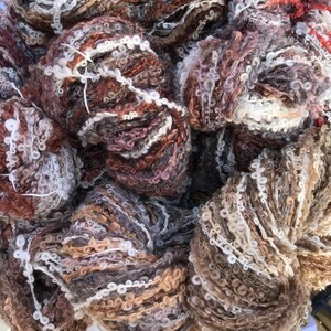 May include: Close-up of a pile of yarn in shades of brown, white, and pink. The yarn has a fluffy, textured appearance.