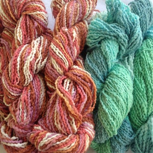 May include: Three skeins of yarn in different colors. The first skein is a mix of pink, white, and brown. The second skein is a light green color. The third skein is a darker green color.