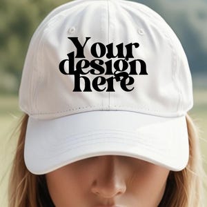 May include: White baseball cap with a black embroidered design that says "Your design here".