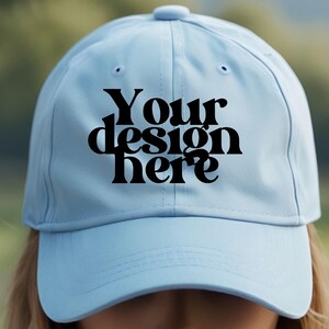 May include: A light blue baseball cap with a black embroidered design that says "Your design here".