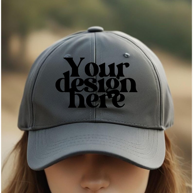 May include: A gray baseball cap with a black embroidered design that says "Your design here".