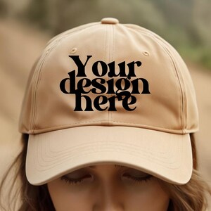 May include: A beige baseball cap with a black embroidered design that says "Your design here".