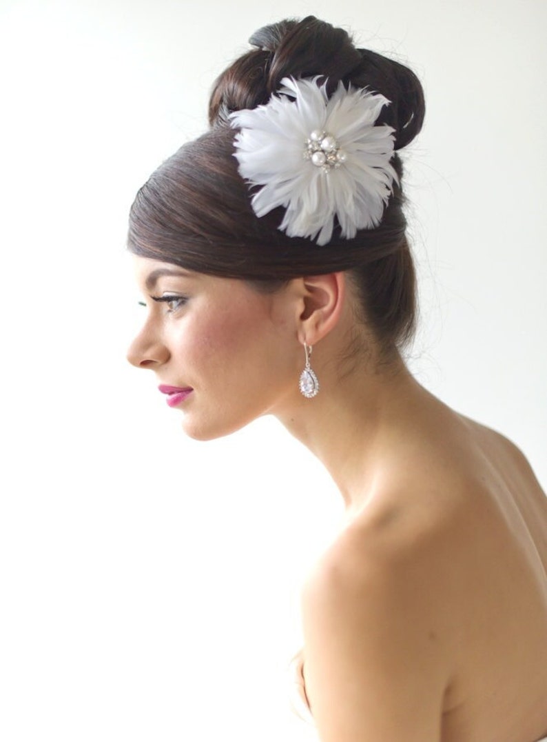 White feather wedding hair clip for bride with a large pearl and rhinestone cluster center.