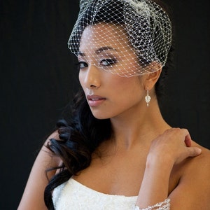 May include: A bride wearing a white wedding dress with a veil and a crystal bracelet. Her hair is styled in a side parting with loose curls.