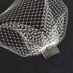 May include: White bridal veil with a comb attached. The veil is made of a fine mesh material.