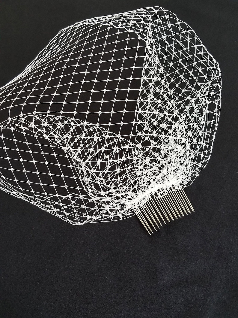 May include: White bridal veil with a comb attached. The veil is made of a fine mesh material.