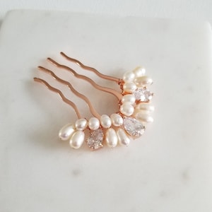 Puede incluir: Un peine de pelo dorado con una fila de perlas blancas y diamantes de imitaci&oacute;n transparentes. El peine est&aacute; dise&ntilde;ado en forma de media luna.
