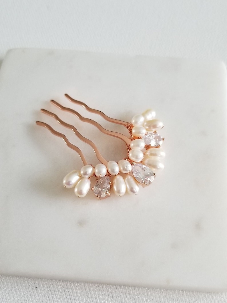 Puede incluir: Un peine de pelo dorado con una fila de perlas blancas y diamantes de imitaci&oacute;n transparentes. El peine est&aacute; dise&ntilde;ado en forma de media luna.