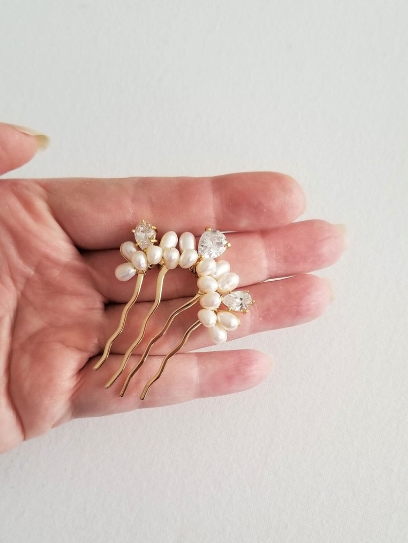 Puede incluir: Peine de pelo dorado con un grupo de perlas blancas y diamantes de imitaci&oacute;n transparentes.
