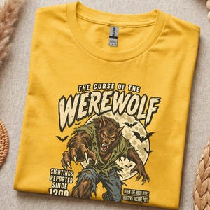 Könnte beinhalten: Ein senfgelbes T-Shirt mit einer Werwolf-Grafik und dem Text "THE CURSE OF THE WEREWOLF", "SIGHTINGS REPORTED SINCE 1200" sowie "WHEN THE MOON RISES HUNTERS BECOME PREY". Das Design zeigt zudem einen Vollmond und mehrere Fledermäuse.