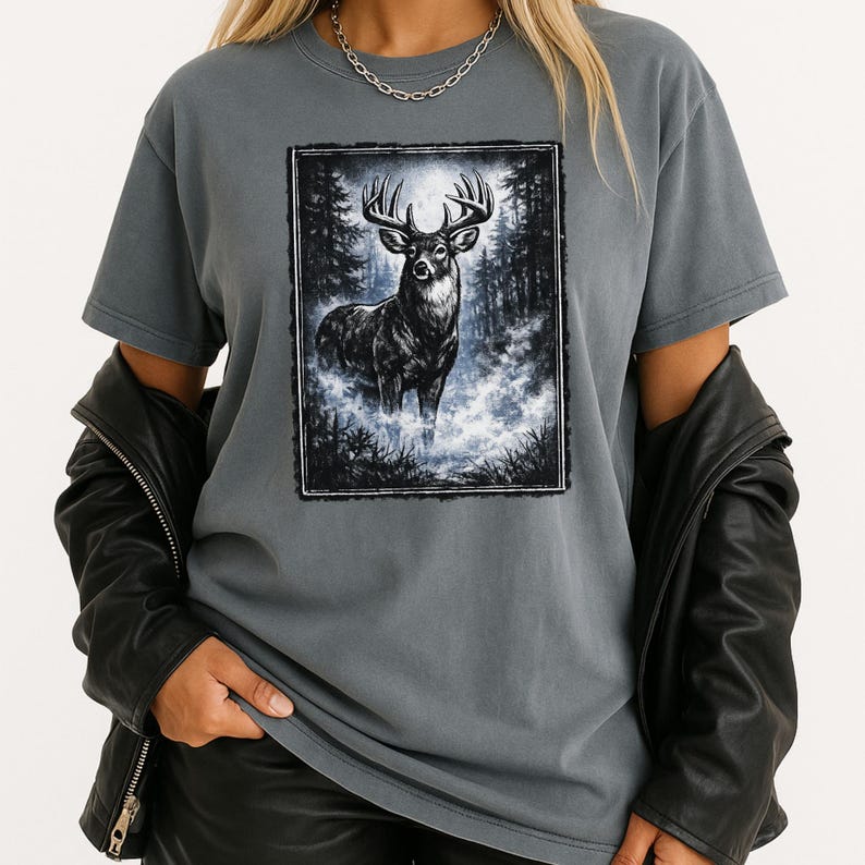 K&ouml;nnte beinhalten: Graues T-Shirt mit einer Schwarz-Wei&szlig;-Illustration eines Hirsches in einer Waldszene. Der Hirsch hat ein gro&szlig;es Geweih und steht in einer nebligen Umgebung. Das Shirt ist einfarbig grau und hat kurze &Auml;rmel.