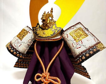 Um capacete adornado com um dragão dourado (estilo século XIII, fabricado no Japão, década de 1990). "Feito à mão por Saburo Uma."