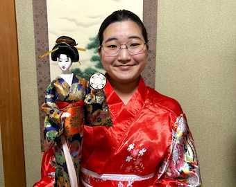 Beautiful and cute geisha doll. Holding a small drum in her hand, she is dressed in a luxurious blue and gold costume. Height: 44.5 cm.