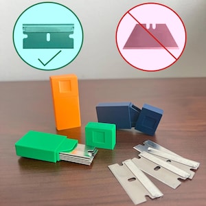 May include: An assortment of razor blades and blade holders in various colors. The image shows a green blade holder with blades, an orange holder, a blue holder, and a green circle with a checkmark next to a blade.