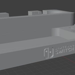 以下が含まれることがあります： グレーの3DプリントされたNintendo Switch 2ドック。ドックは、Nintendo Switchのロゴと数字2が付いた長方形のベースです。コンソールとアクセサリ用のスロットと通気孔があります。
