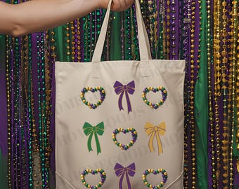 May include: A cream-colored tote bag featuring colorful Mardi Gras-themed designs. The bag has purple, green, and yellow bow and heart-shaped bead designs. The bag is held up by a person's hand.