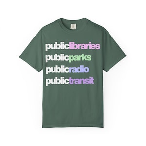 May include: Green t-shirt with the words "public libraries", "public parks", "public radio", and "public transit" in a stacked design. The text is in a gradient of colors, including pink, green, blue, and purple.