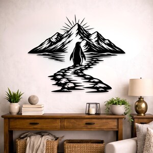 Puede incluir: Arte de pared de metal negro que representa un pingüino caminando hacia una cordillera con un sol naciente. La obra de arte presenta un diseño de silueta detallado, adecuado para la decoración del hogar. El pingüino está en un camino que conduce a las montañas.