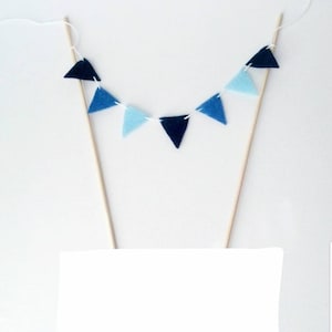 May include: A blue and light blue felt triangle banner cake topper with wooden sticks.