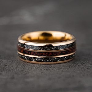 May include: A gold ring with a black and red inlay. The ring has a polished finish and is made of durable metal.