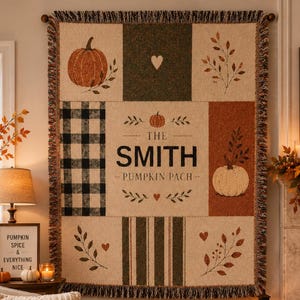 May include: A rectangular woven throw blanket featuring a patchwork design with cream, black, and orange colors. It displays illustrations of pumpkins, leaves, and hearts, with the text THE SMITH PUMPKIN PACH printed in the center. The edges have fringe.