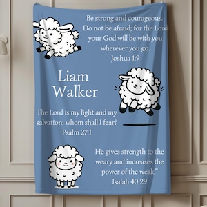 May include: A blue blanket featuring cartoon sheep illustrations and inspirational text. The blanket includes the name "Liam Walker" and Bible verses from Joshua 1:9, Psalm 27:1, and Isaiah 40:29.